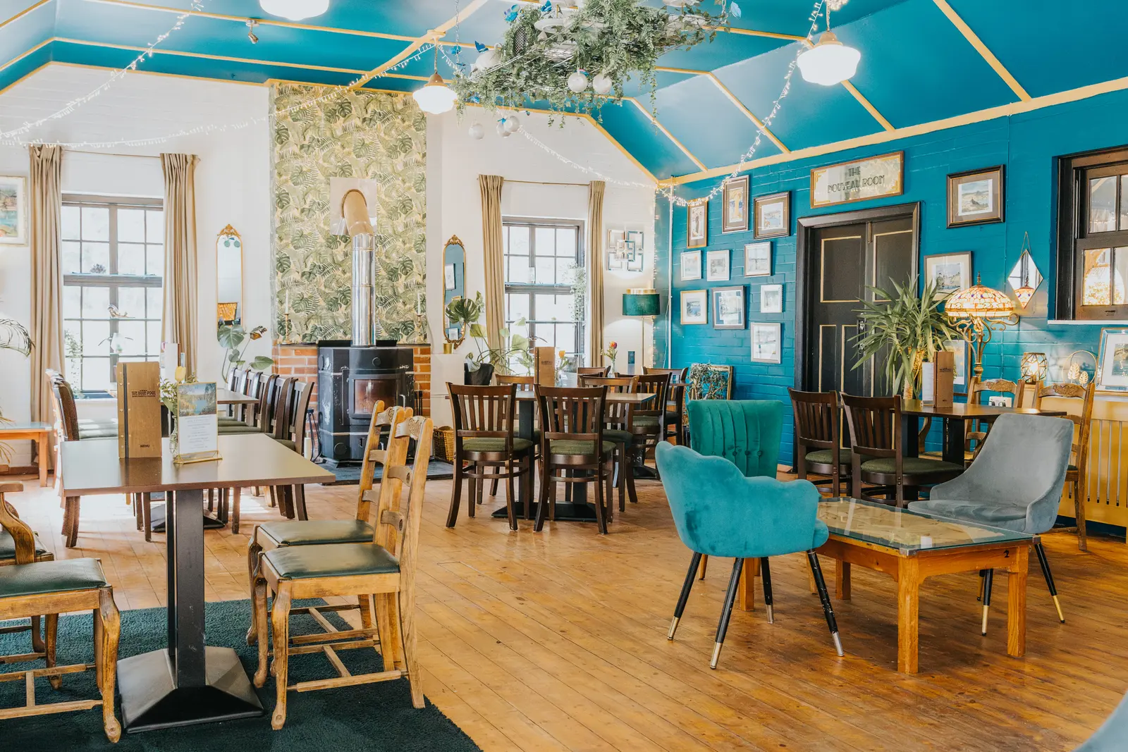 The Blue Pool tea room, teal painted walls, bentwood chairs and framed prints.