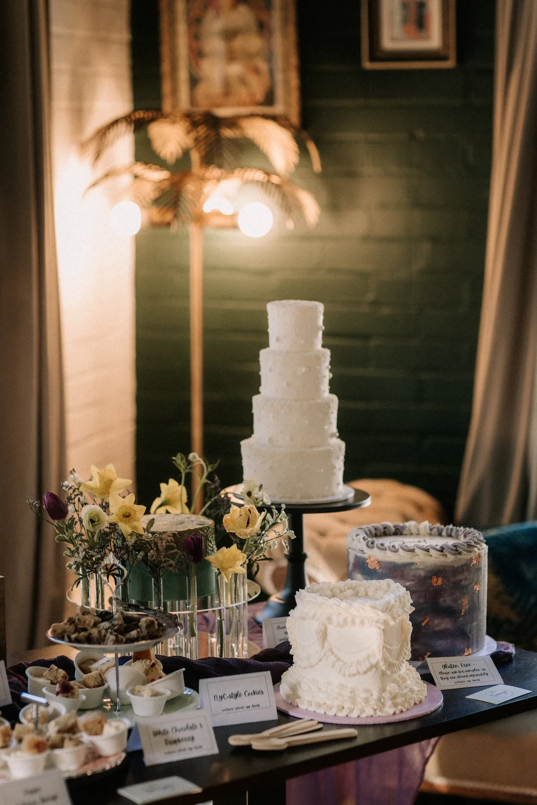 Tiered cakes on stands under a brass palm lamp in the tea room.