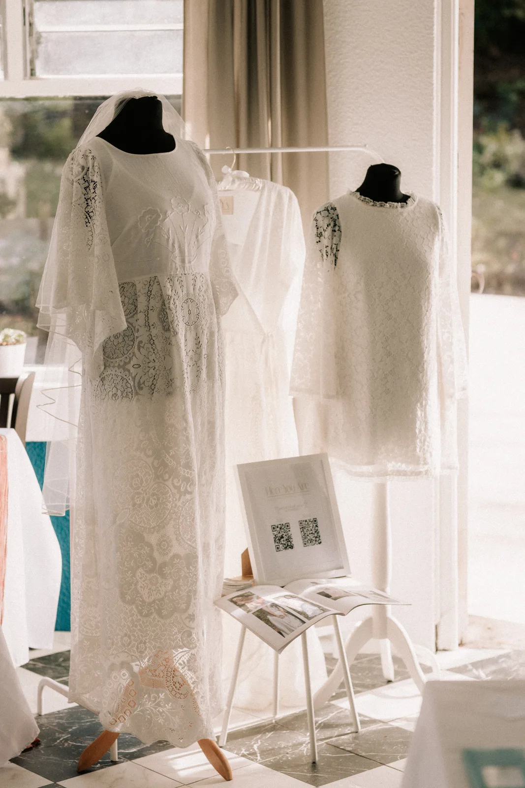 Two lace wedding dresses on mannequins in a bright window.